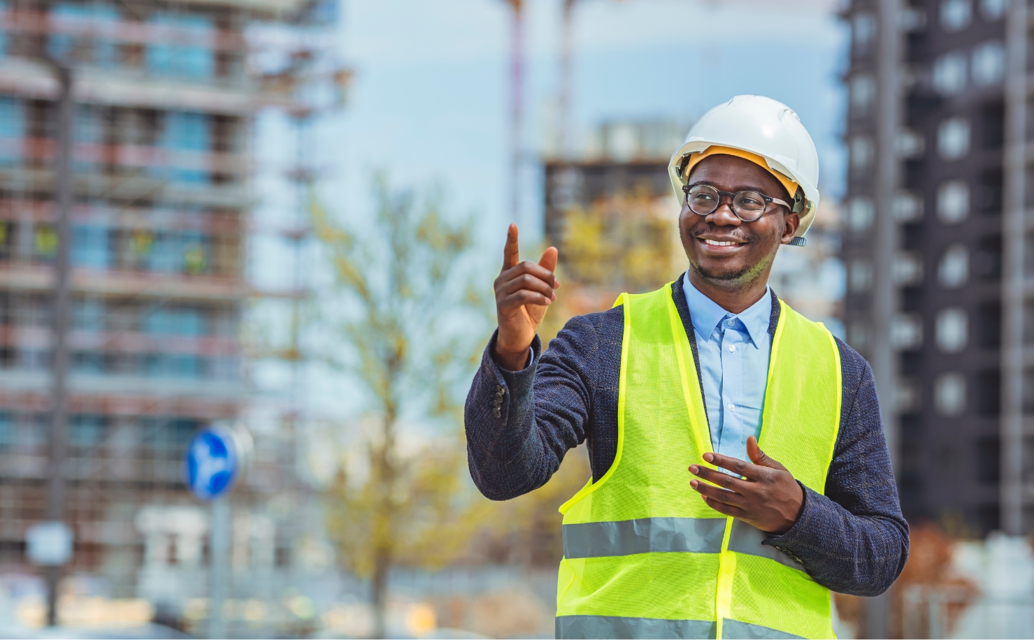 man wearing hi-vis jacket on construction site smiling and pointing